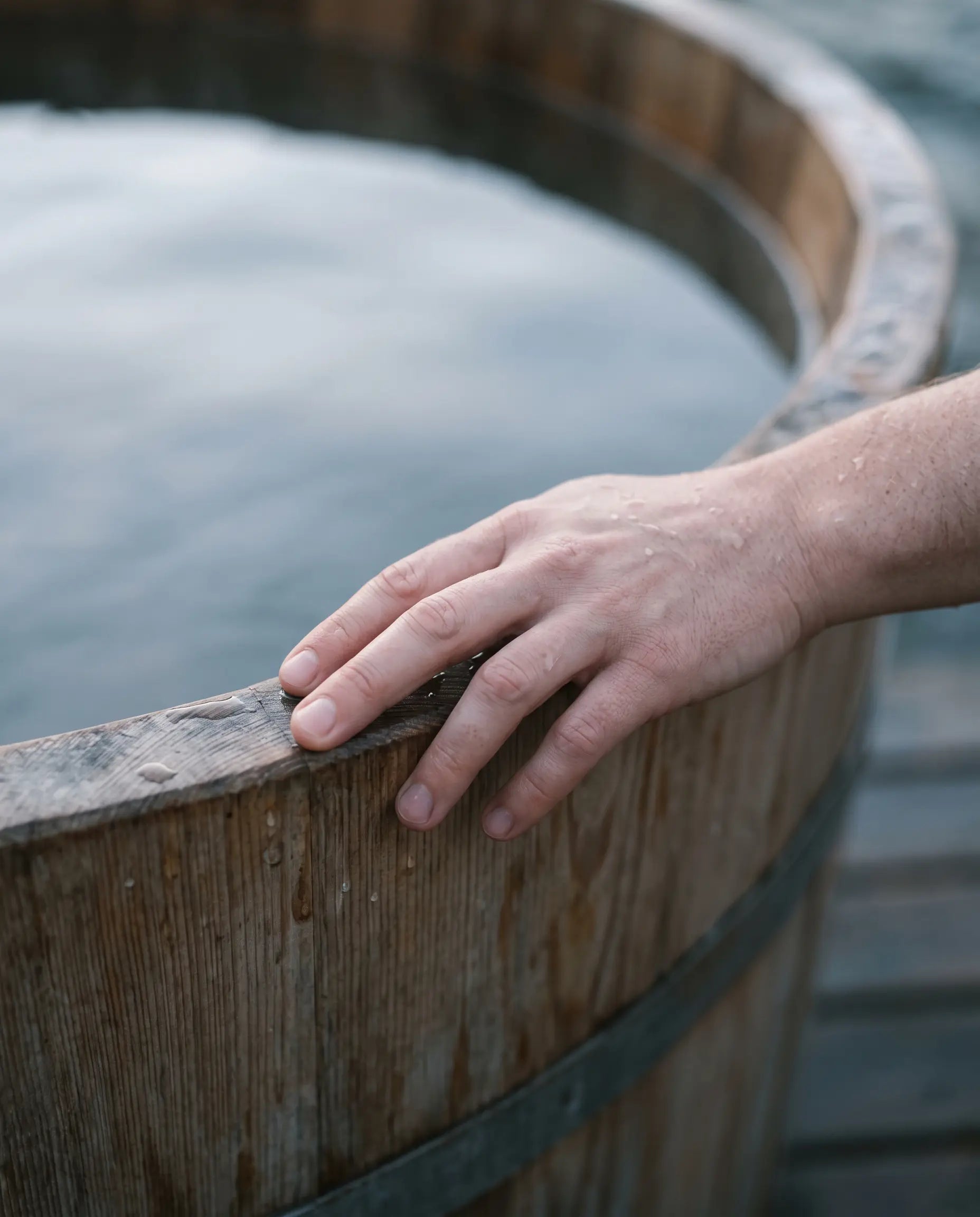 A hand resting on the rim of a cold plunge
